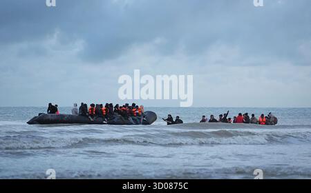 Menschen, die als Migranten gelten, waten durch das Meer, um an Bord eines kleinen Bootes in Gravelines, Frankreich, zu gehen. Bilddatum: Mittwoch, 22. Oktober 2025. Stockfoto