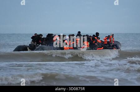 Menschen, die als Migranten gelten, waten durch das Meer, um an Bord eines kleinen Bootes in Gravelines, Frankreich, zu gehen. Bilddatum: Mittwoch, 22. Oktober 2025. Stockfoto