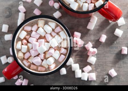 Heißes Schokoladengetränk mit Marshmallows in rotem Becher auf Holztisch Stockfoto