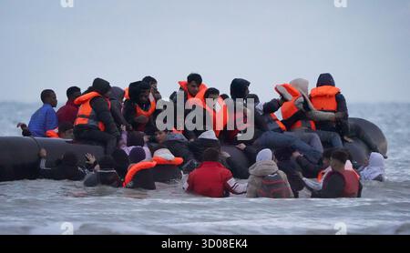 Menschen, die als Migranten gelten, waten durch das Meer, um an Bord eines kleinen Bootes in Gravelines, Frankreich, zu gehen. Bilddatum: Mittwoch, 22. Oktober 2025. Stockfoto