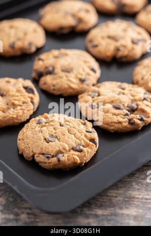 Nahaufnahme von hausgemachten Schokoladenkeksen, die auf einem schwarzen Backblech abkühlen. Stockfoto