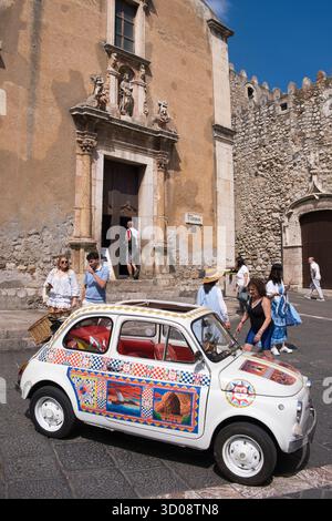 Touristen posieren für Fotos neben einem klassischen Fiat 500 in Taormina, Sizilien, Italien Stockfoto