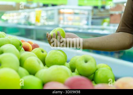 Von Hand einen frischen grünen Apfel aus einem Haufen grüner und roter Äpfel auf einem Markt pflücken. Gesunde Ernährung, Fruchtauswahl und Konzept für frische Produkte. Stockfoto