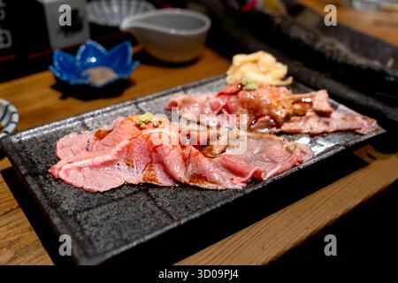 Japanisches Wagyu-Rindfleisch-Sushi, serviert auf einer schwarzen Keramikplatte, garniert mit Wasabi und Sojasauce, in einem traditionellen Restaurant. Stockfoto