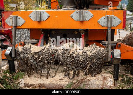 Nahaufnahme von Details zu Forstmaschinen mit Metallketten und Sägemehl während der Holzbearbeitung Stockfoto