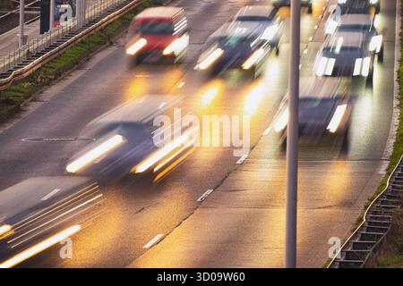 Während der abendlichen Hauptverkehrszeit sind verschwommene Autos auf einer stark befahrenen Straße unterwegs Stockfoto
