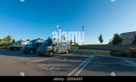 Eine Reihe von Lieferwagen steht auf einem Parkplatz. Die Lieferwagen stehen in einer Reihe und weisen alle in die gleiche Richtung Stockfoto