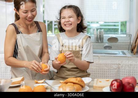 Gemeinsame Aktivitäten während der Feiertage. Eltern und Kinder essen zusammen, Mutter bereitet das Frühstück für die Tochter am Morgen vor, genießen Sie, kleine Stockfoto