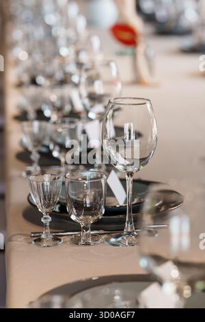 Ein wunderschön gestalteter Tisch für Hochzeit oder formelle Veranstaltung mit Kristallgläsern, schwarzen Tellern und weicher beigefarbener Bettwäsche sorgt für eine Atmosphäre von Stockfoto