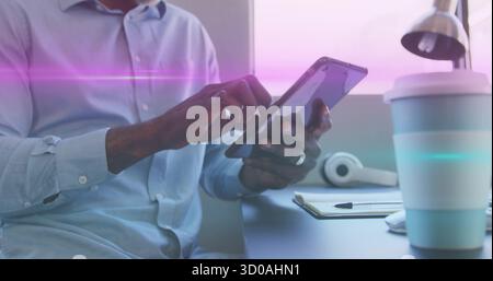 Mitarbeiter in blauem Hemd mit Tablet am Schreibtisch, mit Klemmbrett, Kopfhörern, Kaffeetasse und Lampe klopfen Stockfoto