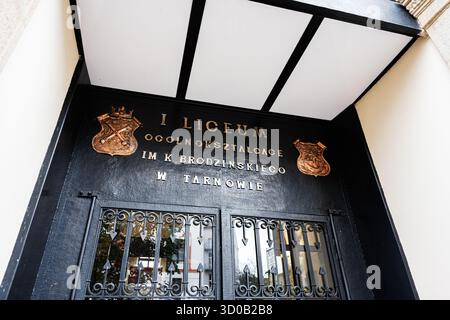 Tarnow, Polen - 10. Oktober 2025: Historischer Schuleingang in Tarnow mit Metalltüren und goldenen Emblemen. Stockfoto