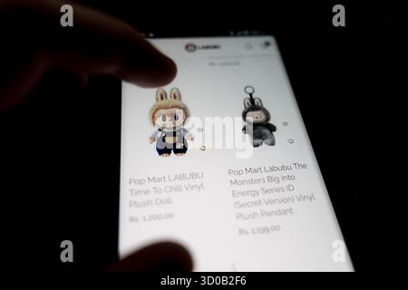 Pop-Mart Labubu The Monsters im Online-Shop. Eine Hand, die einen dunklen Smartphone-Bildschirm durchblättert und eine Produktseite für einen Pop-Mart-Blind anzeigt Stockfoto