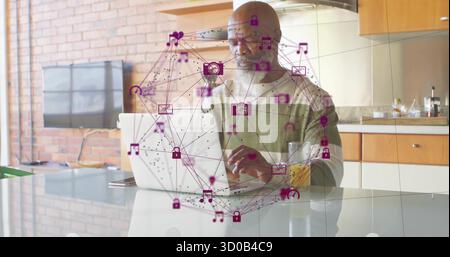 Arbeitender Afroamerikaner, der auf einem Laptop auf einer modernen Kücheninsel tippt und lila Ikonen zeigt Stockfoto