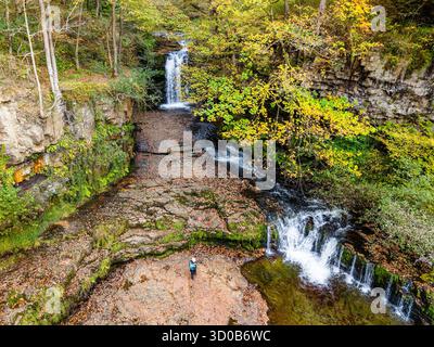 Wanderer erkunden eine malerische Schlucht mit kaskadierenden Wasserfällen im Herbst in Wales Stockfoto