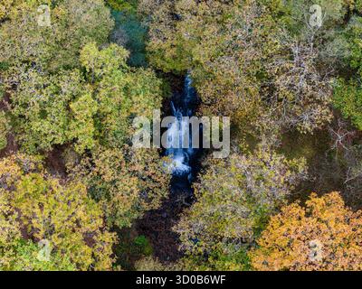 Drohnenblick auf den ISAF-Wasserfall Sgwd Ddwli in einer von Herbstbäumen umgebenen Schlucht Stockfoto