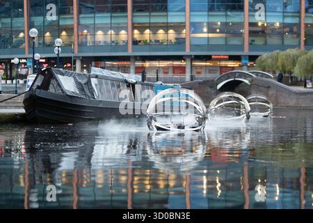Birmingham, Großbritannien. Oktober 2025. Eine faszinierende Flotte von drei beleuchteten Badeskulpturen, die über die Kanäle von Birmingham und dem Black Country aufführen werden, lässt ihr Mädchen heute im Kanal im Stadtzentrum von Birmingham „schwimmen“. Der Künstler Michael Candy hat Water Bots als bahnbrechende Fusion von Kunst und Technik geschaffen. Es ist vom industriellen Erbe der Region West Midland inspiriert und wurde von Birmingham Open Media in Auftrag gegeben. Quelle: Peter Lopeman/Alamy Live News Stockfoto