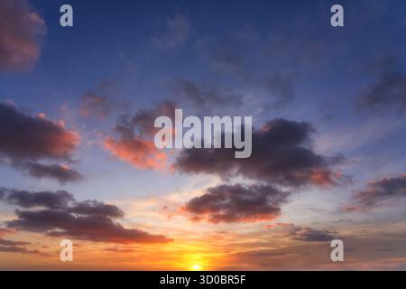 Hochauflösender echter Fotohintergrund eines dramatischen Himmels bei Sonnenuntergang. Leuchtende Farben: Tiefes Blau, Violett und feuriges Orange und rote Wolken am Horizont Stockfoto