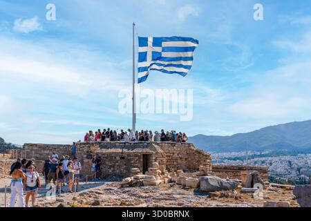 Athen, Griechenland - 24. August 2025: Griechische Flagge winkt auf der Akropolis: Panoramablick auf Athen und die Touristenmassen Stockfoto