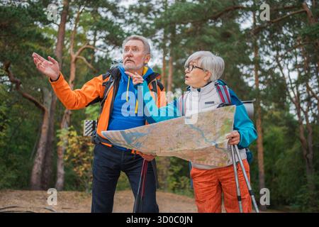 Wandertourismus. Senior Paar Mann Frau, die auf einer Karte auf Papier sucht, genießt Wanderungen im Wald. Glückliche alte Leute Backpacker Wanderer genießen Wandern Wandertourismus Aktivurlaub Schönheit der Natur Stockfoto