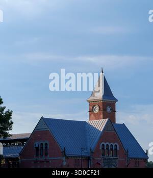 Alter roter Backsteinbahnhof mit steilem Dach und Uhrenturm in Vyborg, Russland, unter blauem Himmel an einem ruhigen Sommertag Stockfoto