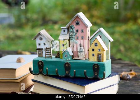 Das skurrile Holzhaus ziert gestapelte Bücher und schafft eine bezaubernde Szene mit einem unscharfen Hintergrund im Freien auf rustikaler Holzoberfläche. Stockfoto