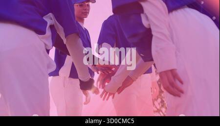 Sechs Baseballspielerinnen, die sich im Sonnenlicht auf dem Grasfeld mit blauen Trikots herumschlagen Stockfoto