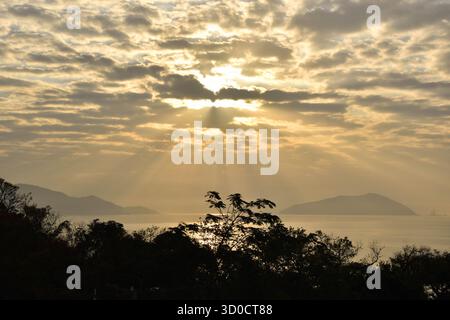 Die Sonnenstrahlen dringen durch die Wolken und auf das Meer auf Lantau Island. Stockfoto