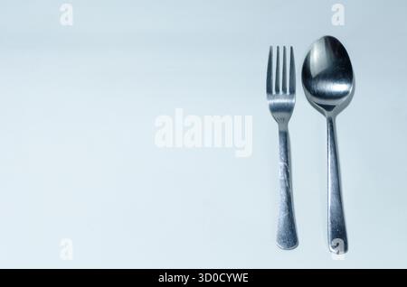 Minimales Besteck: Edelstahlgabel Und Löffel Auf Sauberem Hellblauem Hintergrund Stockfoto