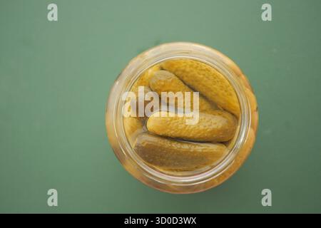 Gurken in einem Glas auf grünem Hintergrund Stockfoto