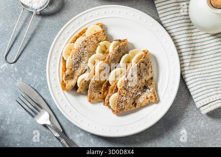 Süße hausgemachte Schokoladen-Bananen-Crepes mit Puderzucker Stockfoto