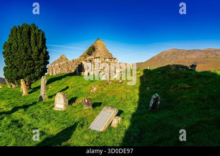 Historische Ruinen der Kirche Cill Chriosd umgeben von alten Grabsteinen und grünem Gras unter einem klaren blauen Himmel Stockfoto