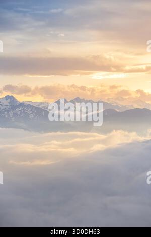 Das Licht des Sonnenuntergangs beleuchtet eine wunderschöne Wolkenumkehr über schneebedeckten Berggipfeln und schafft eine weiche, ätherische Landschaft in den Pyrenäen, Spanien Stockfoto