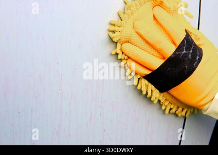 Eine Person wäscht die Karosserie mit einem Schwamm und verwendet dabei ein Reinigungsmittel, das die Rostpartikel verursacht, die in den Lack des Fahrzeugs eingebettet sind. Stockfoto
