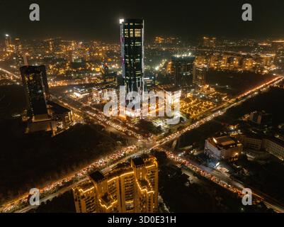 Blick aus der Vogelperspektive auf eine hell beleuchtete Stadtlandschaft mit modernen Gebäuden und dichten Verkehrsadern, die in der Nacht leuchten, Gurugram, Haryana, Indien. Stockfoto