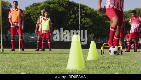 Dribbling Ball, männlicher Fußballspieler in Uniform, navigiert gelbe Kegel auf dem Fußballfeld, Kopierraum Stockfoto