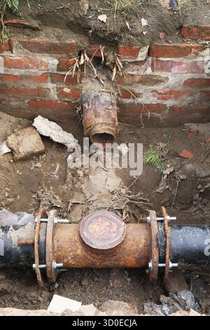 Alte zerstörte Verbindung rostiger Rohre, Bruchstück der Rohre von der roten Ziegelmauer Stockfoto