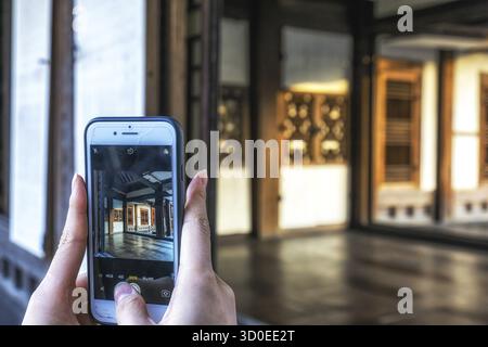 Eine Touristin im Changdeokgung Palast in Seoul, Südkorea, die Fotos mit ihrem Handy macht. Die koreanische Figur am Telefon sagt gerade Foto Stockfoto