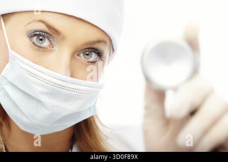 Arzt in schützende Maske und Gummihandschuhe mit Stethoskop Stockfoto