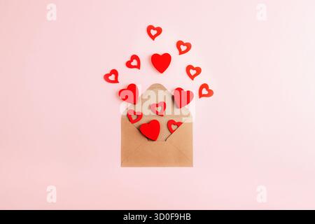 Umschlag mit roten Herzen auf rosa Hintergrund. Grußkarte zum Valentinstag. Draufsicht, flach. Stockfoto