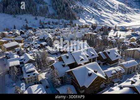 Blick aus der Vogelperspektive auf schneebedeckte Dächer und weißspitzenförmige Bäume, ein ruhiges Winterdorf eingebettet zwischen schneebedeckten Bergen, Andermatt, Schweiz. Stockfoto