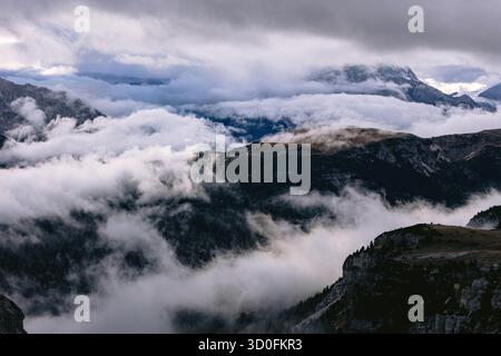 Aus der Vogelperspektive auf die dramatischen, wolkenumhüllten Gipfel der Tre Cime di Lavaredo, die durch die nebelige Landschaft des Auronzo di Cadore, Veneto, Italien, durchdringen. Stockfoto