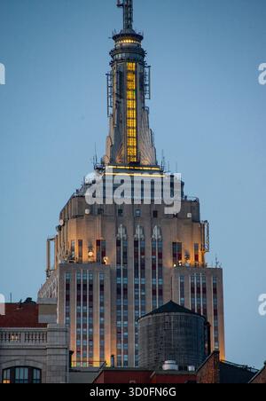 Der Blick auf das Empire State Building erhebt sich majestätisch vor dem dunklen Himmel, seine Art-Deco-Architektur leuchtet warm und steht im Kontrast zur Stadt New York, New York, USA. Stockfoto