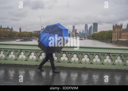 Am 23. Oktober 2025 überwindet Fußgänger starke Winde vom Sturm Benjamin auf der Westminster Bridge Stockfoto