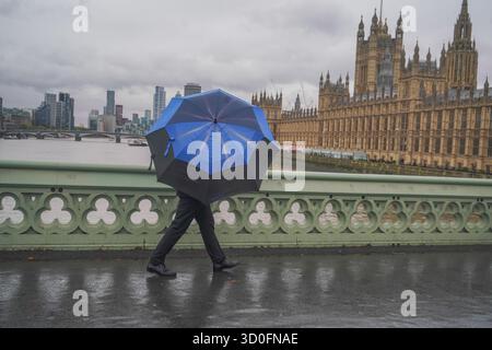 Am 23. Oktober 2025 überwindet Fußgänger starke Winde vom Sturm Benjamin auf der Westminster Bridge Stockfoto