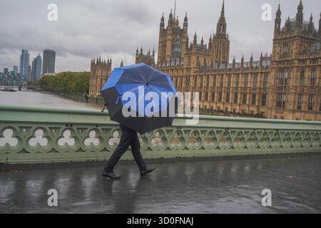 Am 23. Oktober 2025 überwindet Fußgänger starke Winde vom Sturm Benjamin auf der Westminster Bridge Stockfoto