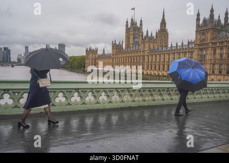 Am 23. Oktober 2025 überwindet Fußgänger starke Winde vom Sturm Benjamin auf der Westminster Bridge Stockfoto