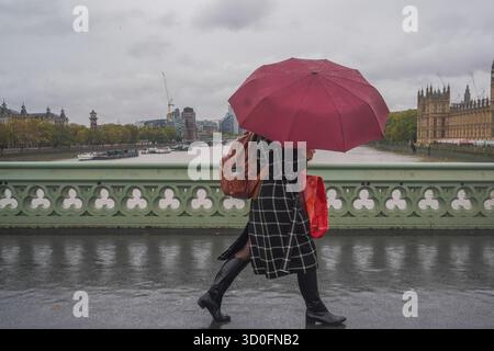 Am 23. Oktober 2025 überwindet Fußgänger starke Winde vom Sturm Benjamin auf der Westminster Bridge Stockfoto