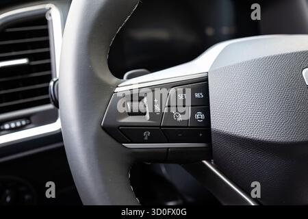 Audiolautstärke, Tempomat und verschiedene andere Tasten am Lederlenkrad eines neuen Fahrzeugs. Nahaufnahme, keine Leute Stockfoto