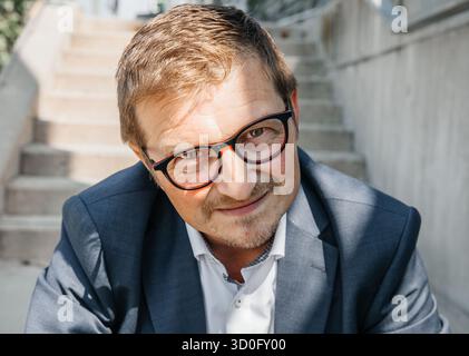 Kaukasischer reifer Mann in Brille und Anzug, der draußen lächelt. Stockfoto