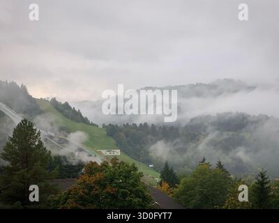 Nebelige Alpenlandschaft mit Olympischen Schanzen und Wald bei Garmisch-Partenkirchen, Bayern, Oktober 2019 Stockfoto